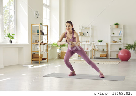 Sporty athletic woman exercising at home on the floor. Fitness and home training concept. Sporty athletic woman exercising at home on the floor. Fitness and home training concept. 135652826