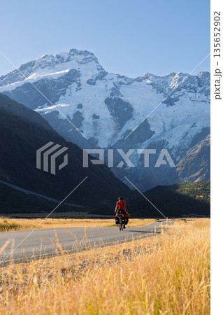 Cyclist touring past massive Mount Sefton glacier near Mount Cook, New Zealand Cyclist touring past massive Mount Sefton glacier near Mount Cook, New Zealand 135652902