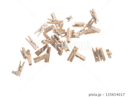 Wooden clothespins float gracefully in air, purposeful clips and holds transformed into a dance of household order and creative inspiration. Beige bundle of laundry dangles. White background isolated 135654017