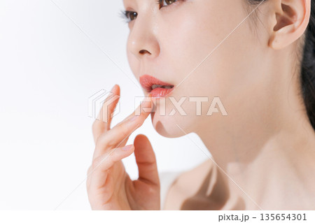 唇に手を当てる若い女性 135654301