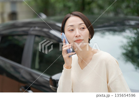 車の前に立って電話をする女性 車の前に立って電話をする女性 135654596