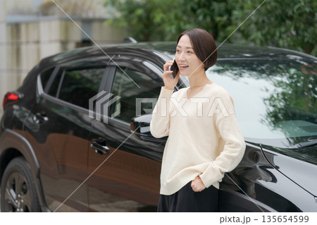 車の前に立って電話をする女性 135654599