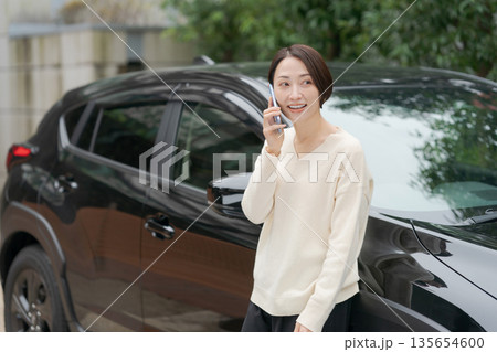 車の前に立って電話をする女性 135654600