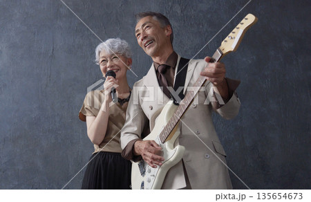 シニアのミュージシャン 男性のギタリストと女性のボーカル 黒背景 シニアのミュージシャン 男性のギタリストと女性のボーカル 黒背景 135654673