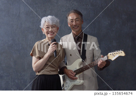 シニアのミュージシャン 男性のギタリストと女性のボーカル 黒背景 カメラ目線 シニアのミュージシャン 男性のギタリストと女性のボーカル 黒背景 カメラ目線 135654674