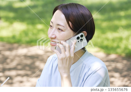 屋外でスマートフォンで電話する女性 屋外でスマートフォンで電話する女性 135655676