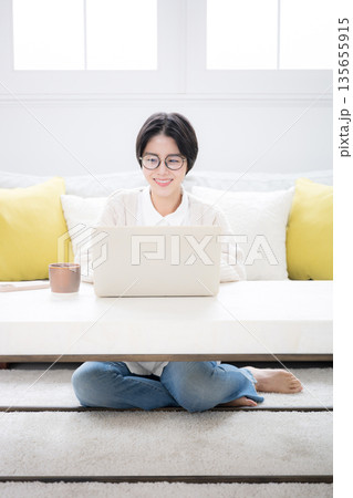 部屋でニットを着てスマホをタップ、見るショートカットの女性 春秋冬の優しい明るいイメージ 部屋でニットを着てスマホをタップ、見るショートカットの女性 春秋冬の優しい明るいイメージ 135655915