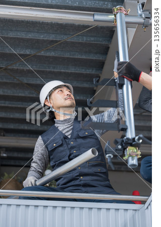 天井が近い高所の足場で単管パイプを固定するクランプなどの施工作業　鳶職や作業員のイメージ　レンチ 135656334