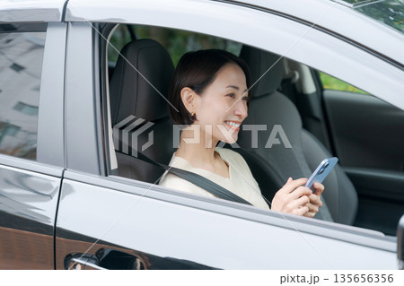 運転席でスマホを見る女性 運転席でスマホを見る女性 135656356
