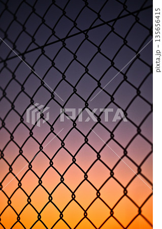 夕暮れの空と金網フェンス 135656415