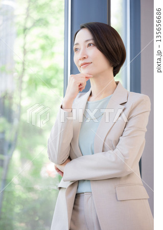 窓際で考えるビジネスマンの女性 キャリアに悩む転職どうしようかな 窓際で考えるビジネスマンの女性 キャリアに悩む転職どうしようかな 135656686