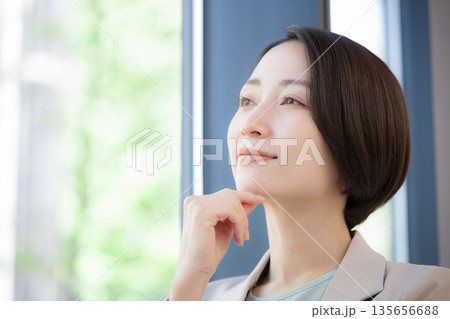 窓際で考えるビジネスマンの女性 キャリアに悩む転職どうしようかな 窓際で考えるビジネスマンの女性 キャリアに悩む転職どうしようかな 135656688