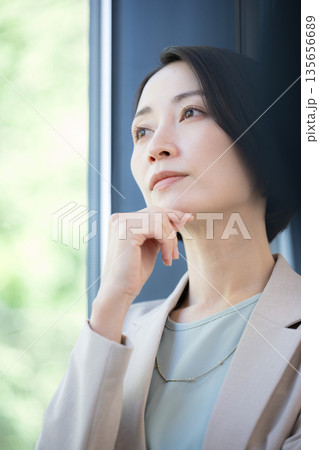 窓際で考えるビジネスマンの女性　キャリアに悩む転職どうしようかな	 135656689