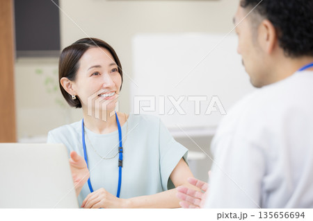 お客様や同僚と説明や打ち合わせをする名札を付けた営業女性などの爽やかなイメージ 説明やプレゼン 春夏 お客様や同僚と説明や打ち合わせをする名札を付けた営業女性などの爽やかなイメージ 説明やプレゼン 春夏 135656694