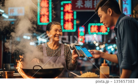 アジアの夜市でキャッシュレス決済を導入する屋台の店主 135657383