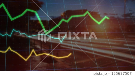 Displaying tri color line graph curves over gridlines, blurred rural railway at dusk with sun flare 135657507