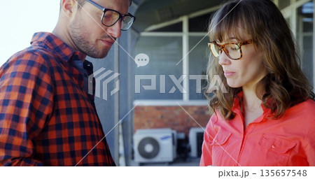 Discussing repair details two coworkers standing on exterior veranda, with AC condenser unit 135657548