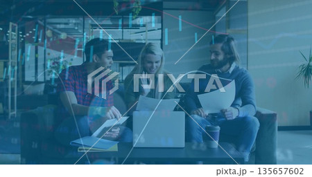 Discussing details colleagues gesturing toward laptop reviewing documents in office lounge 135657602