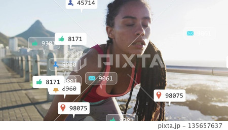 Leaning female in sportswear catching breath on railing at promenade, with floating social icons 135657637