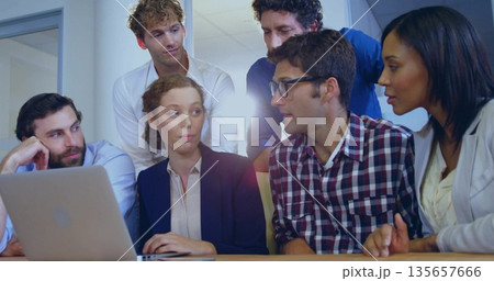 Collaborating business casual professionals typing and discussing around laptop on table in office Collaborating business casual professionals typing and discussing around laptop on table in office 135657666
