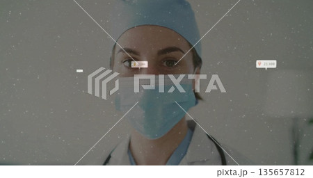 Standing professional wearing white coat with surgical cap and mask in exam room, with stethoscope 135657812