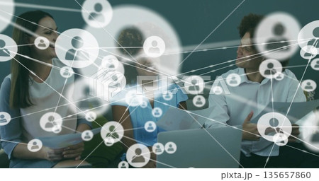 Collaborating professionals reviewing network overlay in office lounge, with laptop and documents 135657860