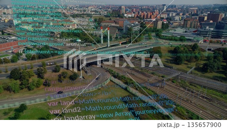 Showing highway overpass, exit ramps curving above railway tracks in urban area, with code overlay 135657900