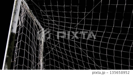 Framing white soccer goalpost with net standing on sports field at night, with chipped paint Framing white soccer goalpost with net standing on sports field at night, with chipped paint 135658952