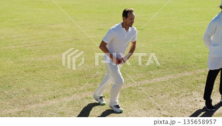 Running cricketer in uniform preparing to bowl on cricket pitch with red ball, markings, copy space Running cricketer in uniform preparing to bowl on cricket pitch with red ball, markings, copy space 135658957
