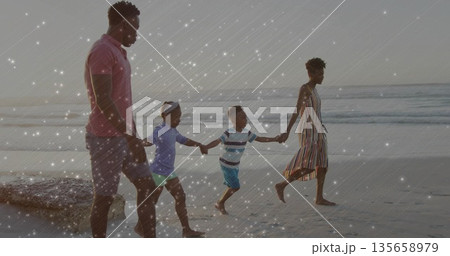 Walking family of four holding hands along wet shoreline at sandy beach, pastel sky Walking family of four holding hands along wet shoreline at sandy beach, pastel sky 135658979