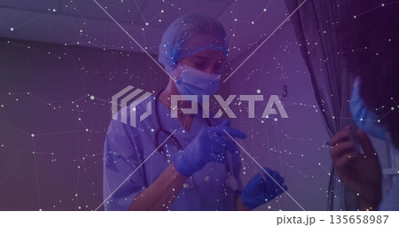 Gesturing masked nurse in scrubs conducting consultation in area 3, with stethoscope and curtain 135658987