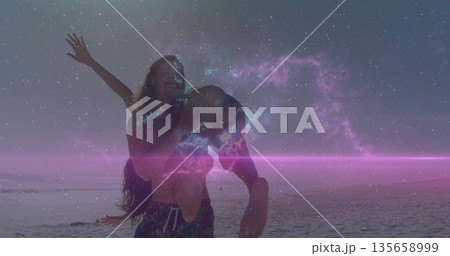 Muscular shirtless man carrying swimwear-clad woman on sandy ocean shoreline, cosmic nebula sky 135658999