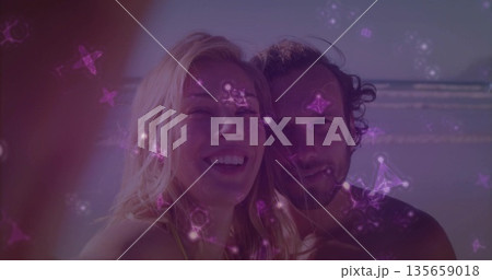 Posing man and woman smiling at recorder on beach with waves, animated constellations drifting 135659018