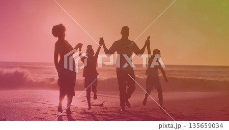Jumping family of four holding hands barefoot along shoreline at dusk, wet sand waves footprints Jumping family of four holding hands barefoot along shoreline at dusk, wet sand waves footprints 135659034