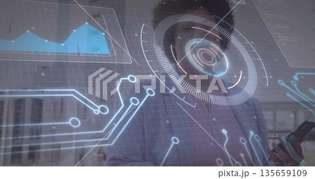Holding smartphone, woman wearing blazer and glasses reviewing holographic interface data in office Holding smartphone, woman wearing blazer and glasses reviewing holographic interface data in office 135659109