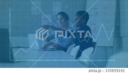 Analyzing data trends on silver laptop by two businesswomen in office meeting room, graph overlay 135659142
