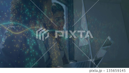 Collaborating businesswomen analyzing glowing waveforms on laptop screen in office by window 135659145