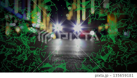 Illuminating vehicle headlights shining across wet road at night, green overlay and blurred lights 135659181