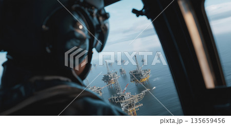 Helicopter pilot wearing headset views offshore oil rigs from cockpit window, multiple platforms visible in the ocean under a cloudy sky Helicopter pilot wearing headset views offshore oil rigs from cockpit window, multiple platforms visible in the ocean under a cloudy sky 135659456