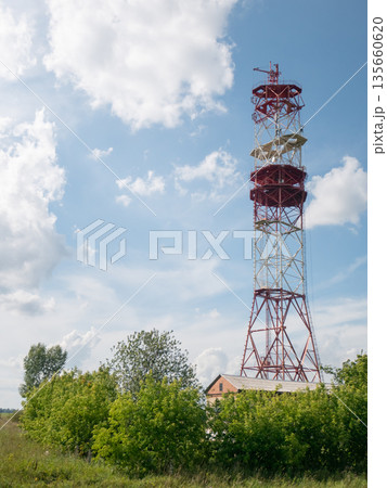 Red and white telecommunication tower under a cloudy sky. Providing wireless communication, television, and radio signal transmission. Red and white telecommunication tower under a cloudy sky. Providing wireless communication, television, and radio signal transmission. 135660620