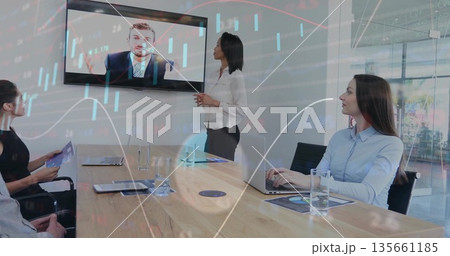 Leading woman in white blouse discussing in meeting room, with laptops and remote speaker on screen Leading woman in white blouse discussing in meeting room, with laptops and remote speaker on screen 135661185