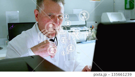 Analyzing network icons senior male doctor holding stethoscope at clinical office desk, copy space 135661239