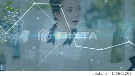 Reacting to data overlays, Asian woman in white blouse speaking at corporate office, with graphs 135661268