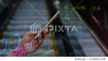 Holding smartphone woman in pink sweater viewing stock market charts over escalator in station 135661339