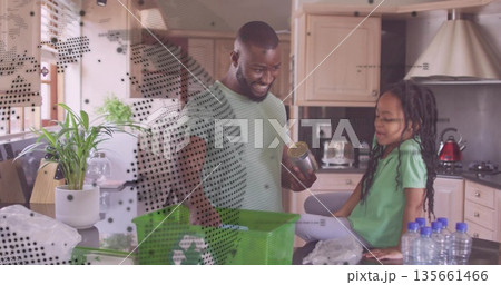 Sorting father and daughter placing recyclables on home kitchen counter, with green recycling bin Sorting father and daughter placing recyclables on home kitchen counter, with green recycling bin 135661466