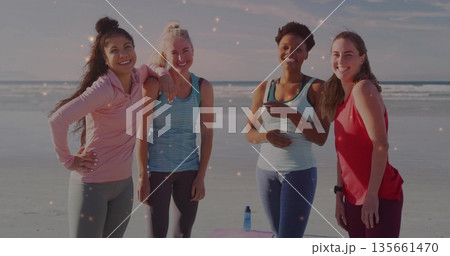 Smiling women exercising in sportswear at beach shore, with pink exercise mat and blue water bottle Smiling women exercising in sportswear at beach shore, with pink exercise mat and blue water bottle 135661470