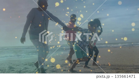 Holding hands grandparents with grandkids walking along beach under golden light and gentle waves Holding hands grandparents with grandkids walking along beach under golden light and gentle waves 135661471