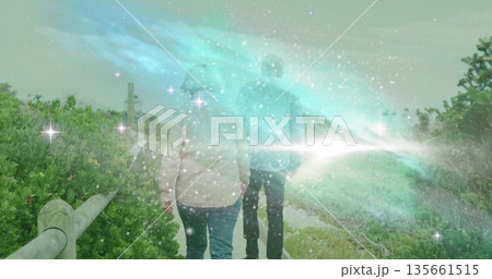 Walking couple wearing jeans on coastal trail with wooden railing and vegetation, ethereal lights Walking couple wearing jeans on coastal trail with wooden railing and vegetation, ethereal lights 135661515