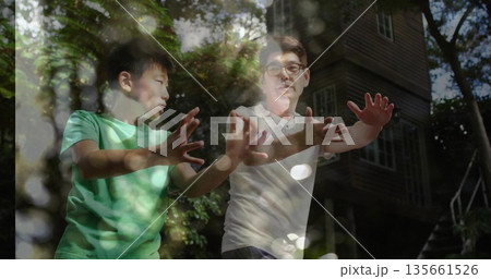 Practicing martial arts father and son extending arms outdoors in forest by cabin, dappled sunlight 135661526