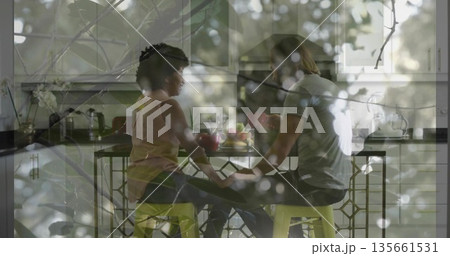 Couple holding hands on yellow stools at modern kitchen island, with fruit bowl and leaf overlay Couple holding hands on yellow stools at modern kitchen island, with fruit bowl and leaf overlay 135661531